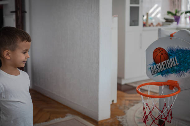A boy practices basketball in the living room