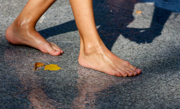 A person's feet are wet and bare on a wet sidewalk. Concept of relaxation and carefree enjoyment of the moment