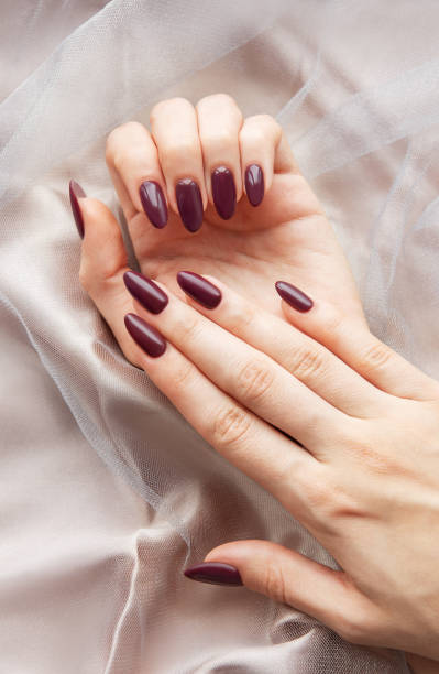 istock Elegant hands with deep burgundy nails resting on soft, sheer fabric in a calm, indoor setting during daytime 2182990022