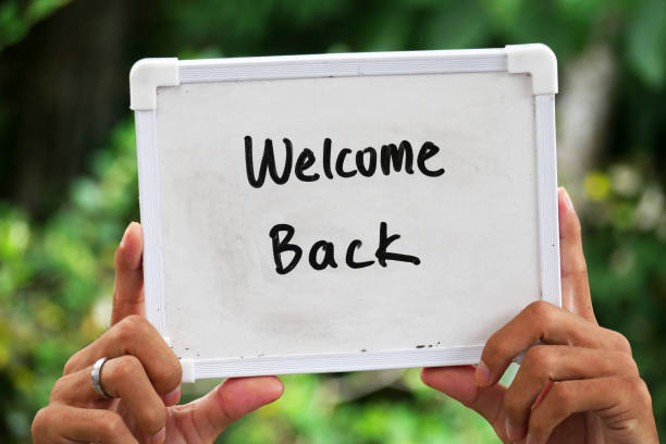 istock hand holding a whiteboard with the words Welcome Back, bokeh nature background 2182992420
