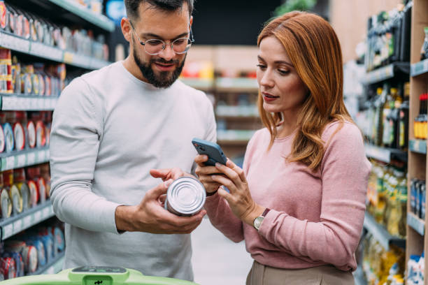 istock Smiling woman scanning QR code on a product while buying in supermarket. 2182993629