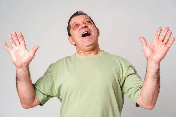 istock A middle-aged man with a neutral expression raises his hands in a questioning gesture against a plain backdrop 2182995867