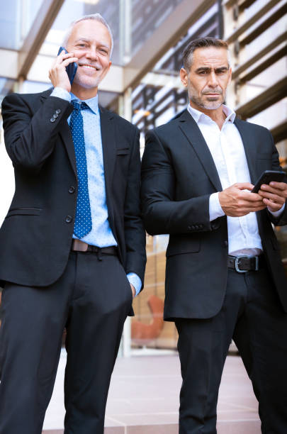 istock Two businessmen talking on their smartphone standing with digital tablet . 2182997914