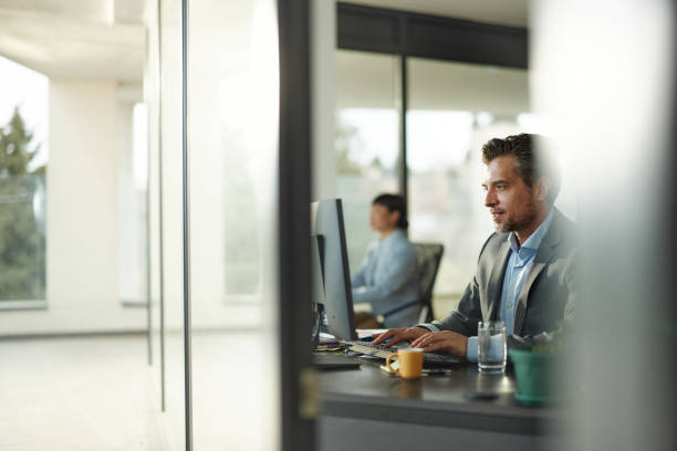 istock Mid adult businessman working on PC at corporate office. 2182998207