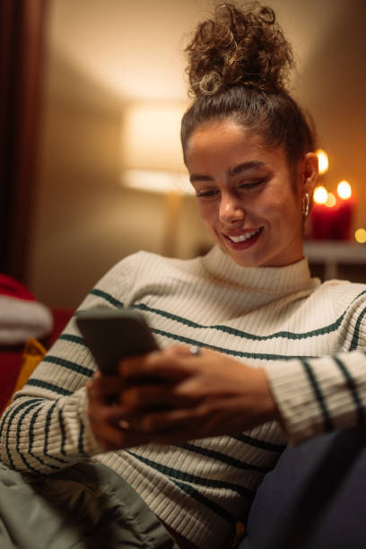 Young woman using smartphone on christmas eve at home