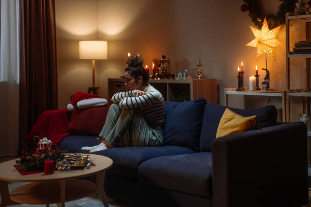 istock Sad woman sitting on sofa during christmas time at home 2182998971