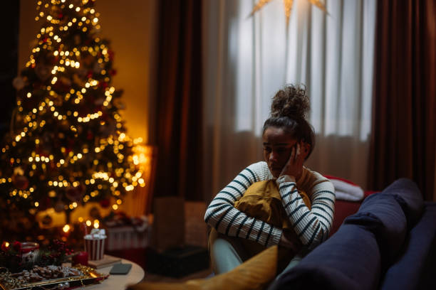 Sad woman sitting on sofa during christmas time feeling lonely