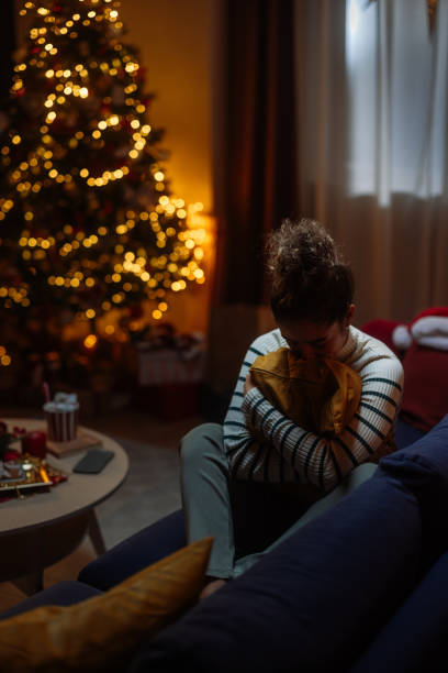 istock Sad woman hugging pillow on sofa during christmas time 2182998980