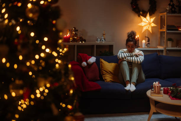 Sad woman sitting alone on sofa during christmas holidays