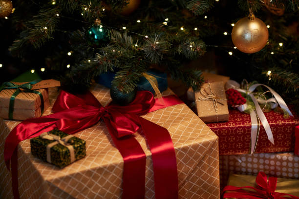 istock Closeup Big Gift Box with Red Bow Piled Under Christmas Tree 2183012694