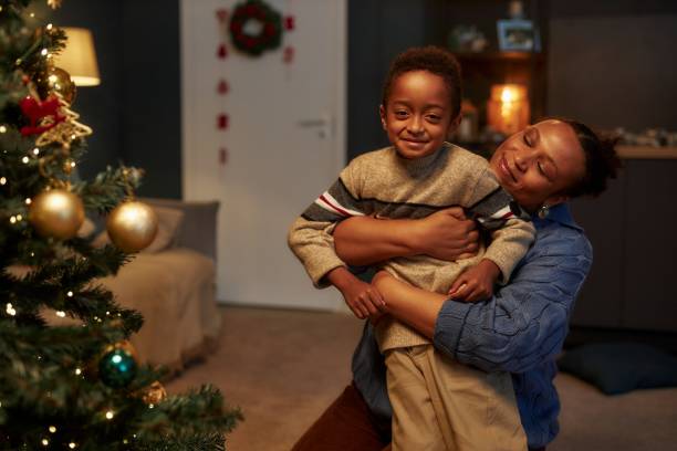 istock Black Mother Embracing Son by Christmas Tree 2183012795