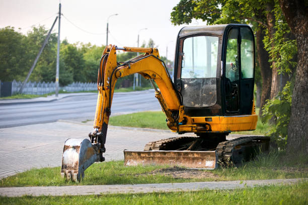 istock Tracked orange mini excavator digger near road green with trees on background with copyspace. 2183014167