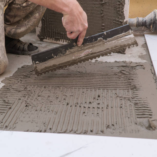 istock A construction worker applies cement for laying floor ceramic tiles with special spatula 2183018736