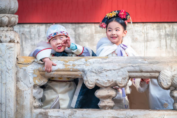 Two children in ancient costumes are playing and make face with each other