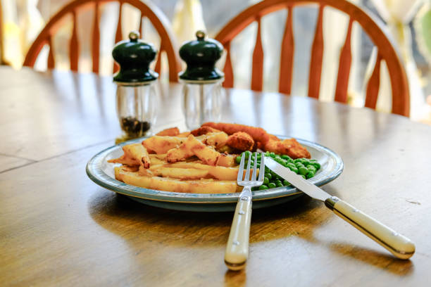 Small kid's meal - chicken nuggets, french fries, carrot and green peas. Colorful dinner on white wooden table. Plate captured from above (top view, flat lay). Layout with free copy (text) space.