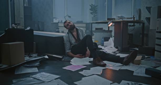 istock Frustrated office worker sits on the floor in destroyed office room 2183021755