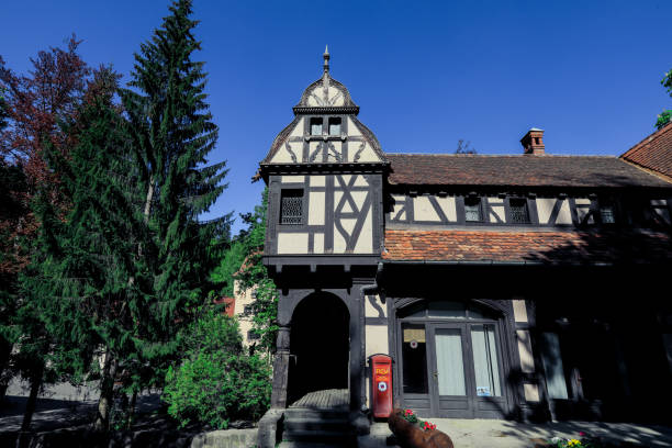Bucharest, Romania - May 23, 2023: A charming building in Bucharest features distinctive traditional architecture highlighted against a clear blue sky. Lush green trees surround the structure enhancing its beauty.