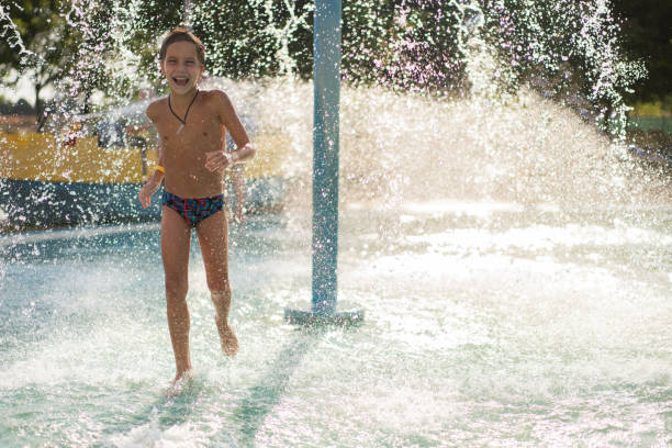istock Boy running under waterfall in water park 2183023526