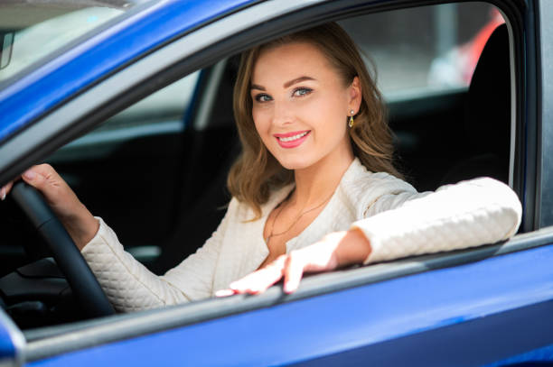 istock Businesswoman smiling while driving her new blue car 2183024317