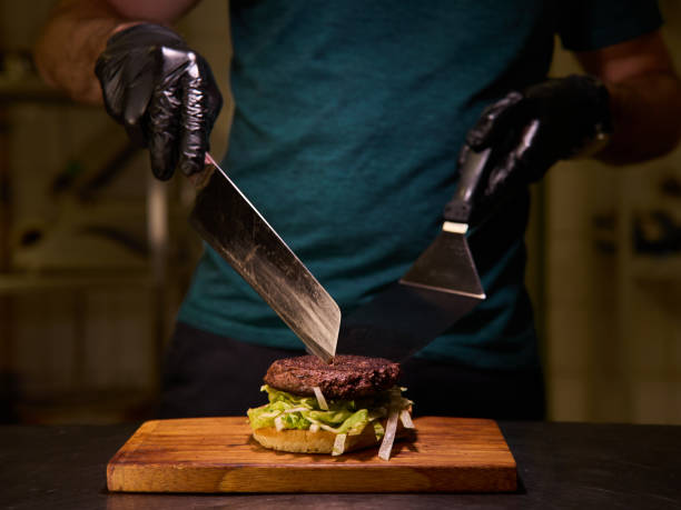 istock A man is cutting a burger on a wooden cutting board 2183024502