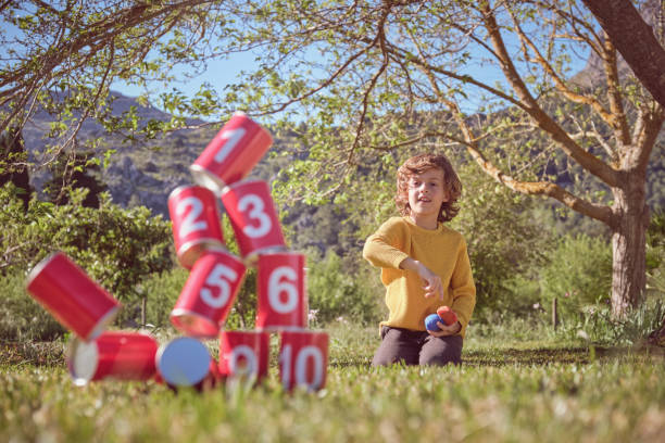 Content boy playing can knockdown game in summer park