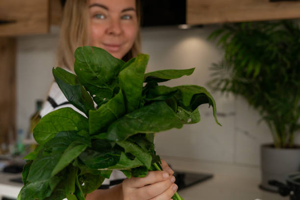 istock Young woman holding fresh spinach in a modern kitchen while preparing a healthy meal 2183038807