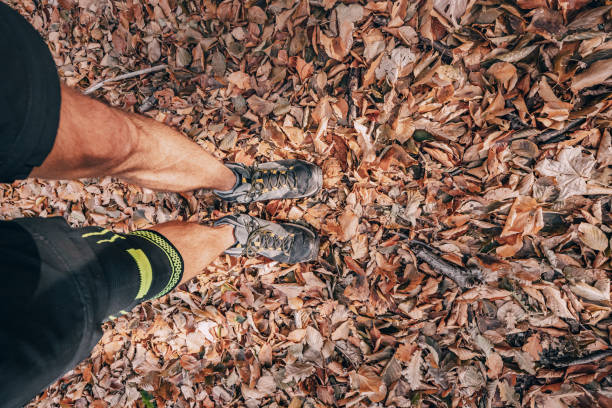 A hiker's legs positioned on a forest trail, featuring a soft knee support bandage on one leg, highlighting the importance of comfort and protection for those with arthritis or meniscus issues