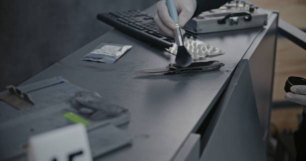 istock Numbered marker stands next to evidence. Rack focus on criminalist searching fingerprints 2183042058