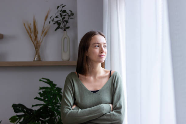 istock Young woman looking out window, contemplating future with hope and positivity 2183042433