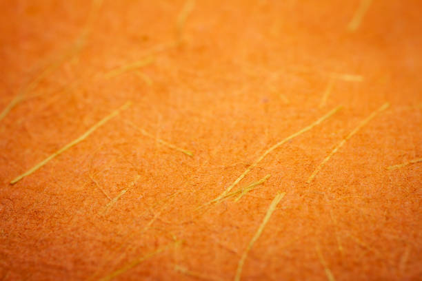Extreme closeup of orange handmade paper with shallow depth of field.