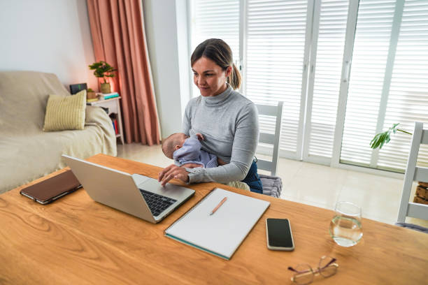istock Young mother working at home while feeding her infant son - Smart working and family concept - Focus on mom face 2183045661