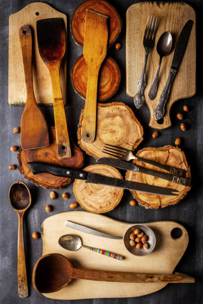 istock Old wooden cutting boards, tree trunk slices, nuts and kitchen utensils on black chalkboard 2183045671