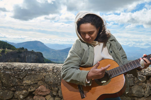 istock Young woman playing guitar outdoors against scenic mountain backdrop 2183050294