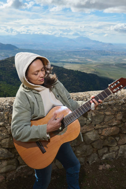istock Woman playing acoustic guitar outdoors with mountain view 2183050302