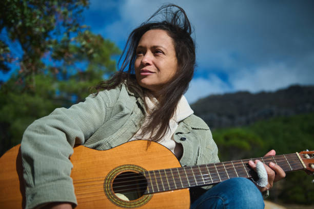 istock Woman playing guitar outdoors surrounded by natural scenery 2183050330