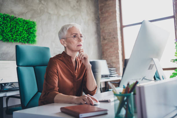 istock Photo of mature old female thoughtful solve problem work computer dressed brown shirt office professional workshop room interior 2183053241