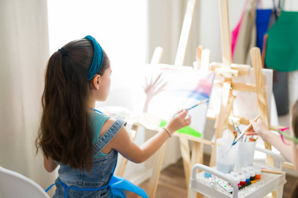 istock Rear view of adorable young student creating artwork on a tiny canvas in a school art class 2183053277