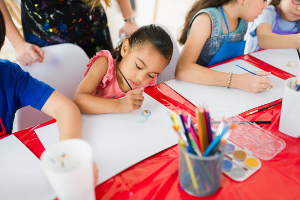 istock Elementary school art class: young students focused on watercolor painting and using colored pencils 2183053803