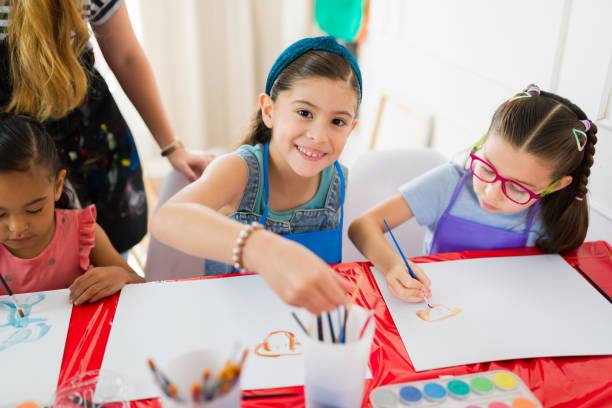 Elementary school hispanic students having fun with watercolor painting in an art class with their teacher