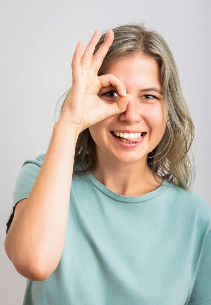 istock Happy young student shows ok sign with hand on eye looking through fingers 2183064151