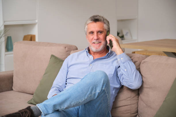 istock Senior man relaxing on sofa and talking on mobile phone at home 2183064208