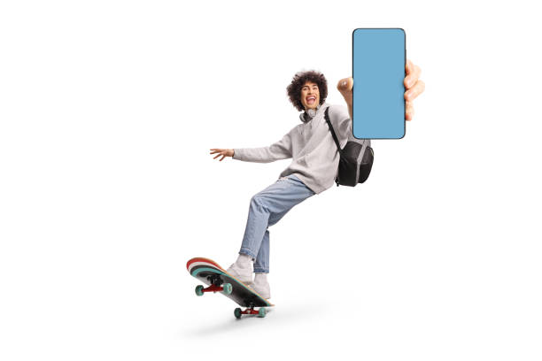 Excited young man riding a longboard and showing a smartphone
