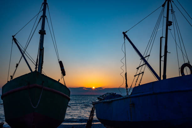 istock Two boats are sitting on the beach at sunset 2183074706
