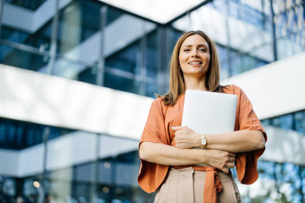 istock Confident woman with laptop, team in background 2183079134