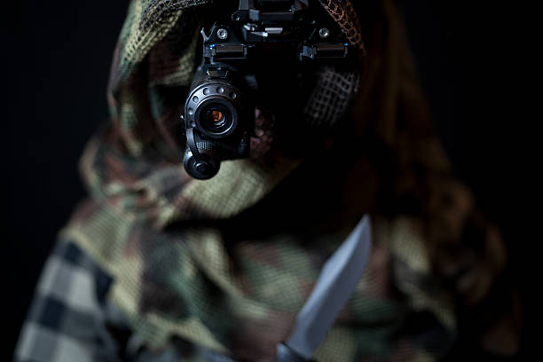 istock A reconnaissance soldier in camo, with a night vision monocular and a sharp knife in his hand. 2183080963
