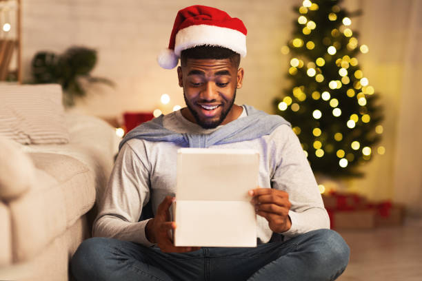 istock Christmas gift. Happy black guy opening box 2183083050