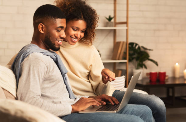 istock Happy afro spouses using laptop, spending weekend at home 2183083207