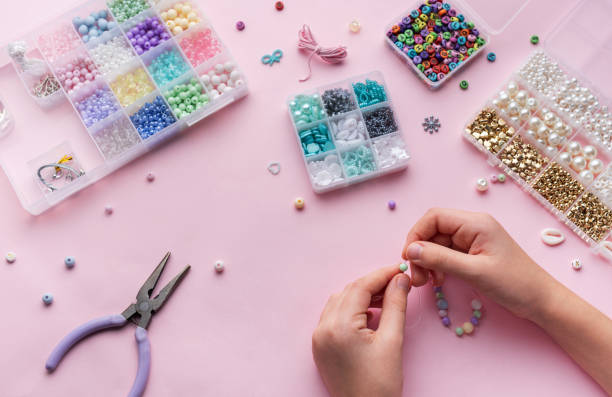 istock Creating colorful beaded jewelry with assorted beads and crafting tools on a light pink surface 2183084267
