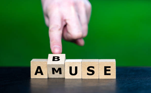 istock Hand turns cube and changes the word amuse to abuse. Awareness for situation which can turn quickly to abuse. 2183087090