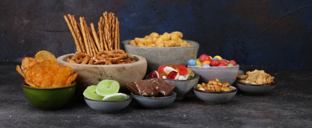 Salty snacks. Pretzels, chips, crackers in wooden bowls on table